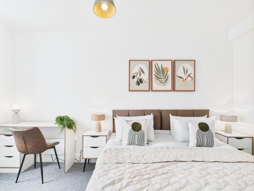 een witte slaapkamer met een groot bed en een bureau bij Spacious Apartment with Private Garden in Norwich