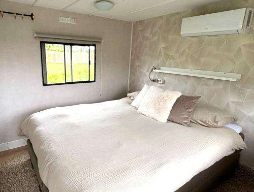 a bedroom with a large white bed and a window at De Polderhoeve in Heerhugowaard
