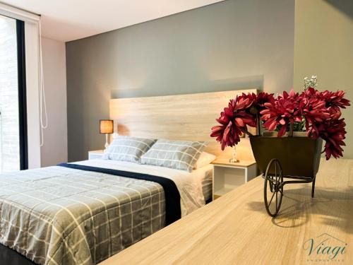a bedroom with a bed and a vase of red flowers at Loft estilo Japonés in Bogotá