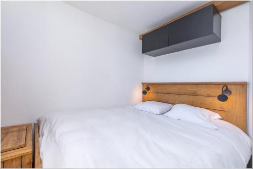 モルジヌにあるAvoriaz 1800 - Tilia appartement de charmeの木製のヘッドボードが付いた白いベッドのある寝室