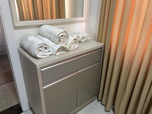 a bathroom with towels on a shelf with a mirror at Apartamento em Foz do Iguaçu, Ravello Residencial in Foz do Iguaçu