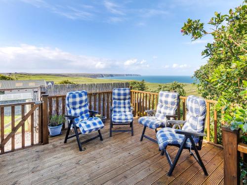 three chairs sitting on a deck with a view of the ocean at Weavers Cottage in Back