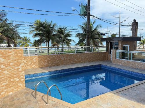 a swimming pool in a house with a brick wall at Pé na Areia Praia do Caiçara in Solemar