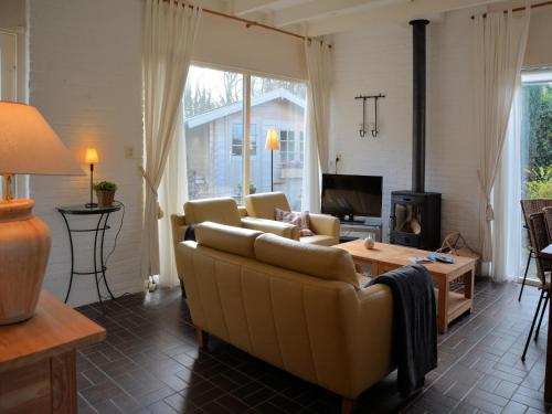 a living room with a couch and a tv at Bungalow in Noordwijkerhout near Lake in Noordwijkerhout