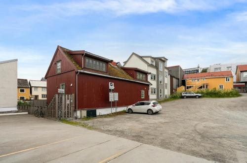 een rood huis met een auto geparkeerd op een parkeerplaats bij Super central studio apartment in Tromsø