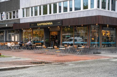 een café met tafels en stoelen voor een gebouw bij Super central studio apartment in Tromsø
