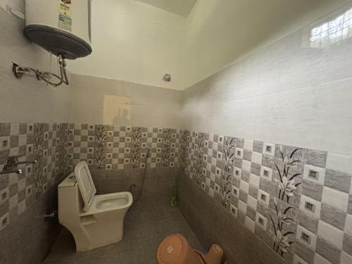 a bathroom with a toilet and tiles on the wall at AP Residency in Uttarkāshi