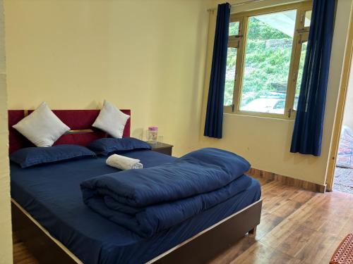 a bedroom with a bed with blue sheets and a window at AP Residency in Uttarkāshi