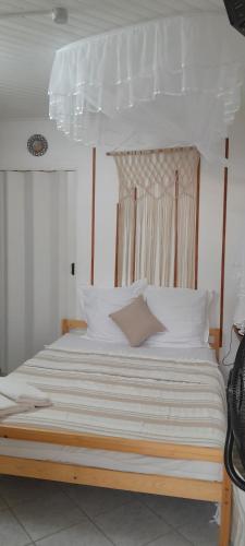 a large bed with white sheets and pillows at O Logis du Morne Jacob, "CANNELLE" Le Morne Rouge Martinique in Le Morne Rouge