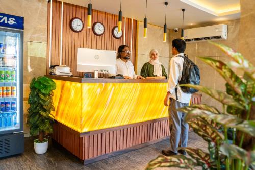 three people standing at a counter in a restaurant at Dubai Frame Residency And Hotel in Thottada