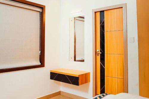 a bedroom with a wooden cabinet and a mirror at Dubai Frame Residency And Hotel in Thottada