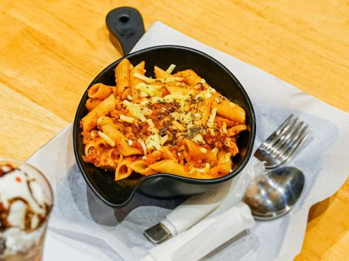 a bowl of pasta on a table with a fork at Dubai Frame Residency And Hotel in Thottada