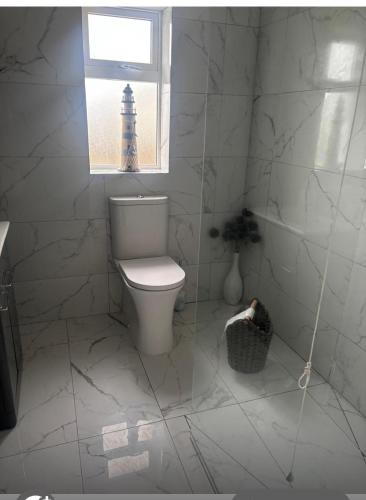 a white bathroom with a toilet and a window at Hollys Cottage in Ahimma