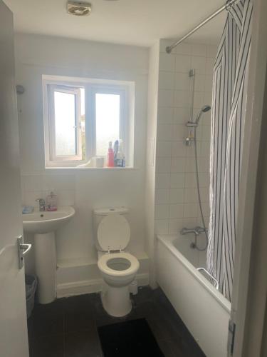 a bathroom with a toilet and a tub and a sink at ComfortVilla LR in Hornchurch