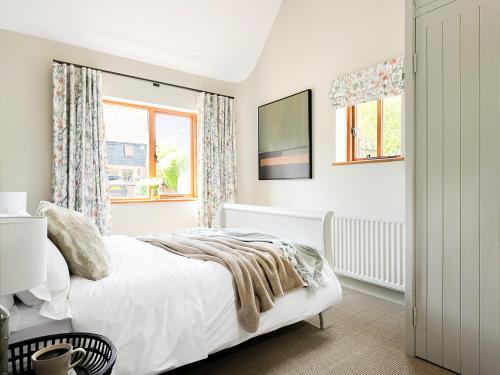 a white bedroom with a bed and two windows at Lantern Lodge in Bramley
