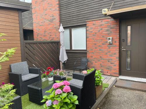 a patio with chairs and an umbrella and flowers at Scandinavian Sleeping & Living Home Stay Experience in Turku