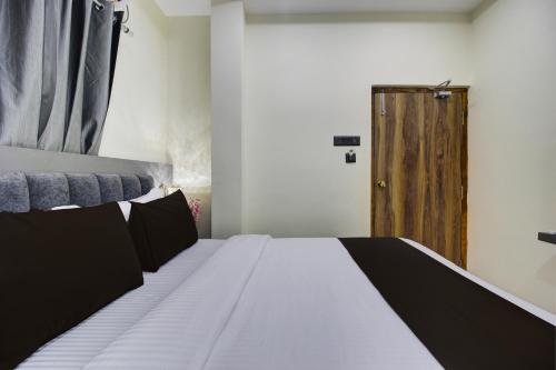 a bedroom with a bed and a wooden door at Super Hotel O EMBASSYINN in Kondapur