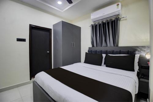 a bedroom with a black and white bed and a black cabinet at Super Hotel O EMBASSYINN in Kondapur