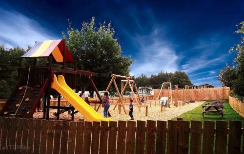 two children playing in a playground with a slide at Slaley Forest Hexham Caravan Retreat Pet Friendly - sleeps 6 in Slaley
