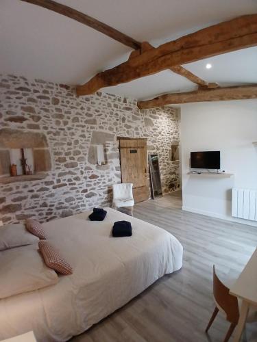 a bedroom with a large bed in a stone wall at Les chambres du Couraud in Saint-Aubin-des-Ormeaux