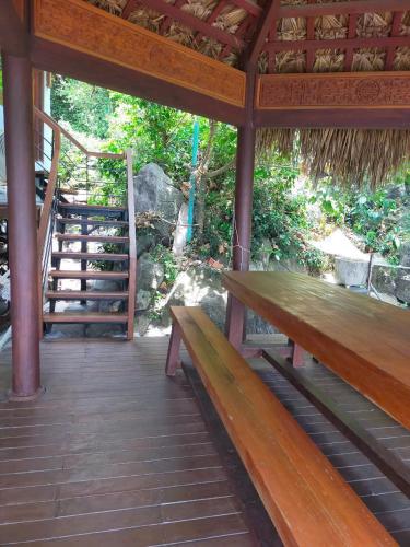 a wooden bench sitting on a porch with a staircase at Cham Island Wooden Cabin in Hoi An