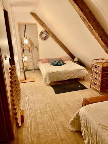 a attic bedroom with two beds and a staircase at Au moulin maison familiale in La Broque