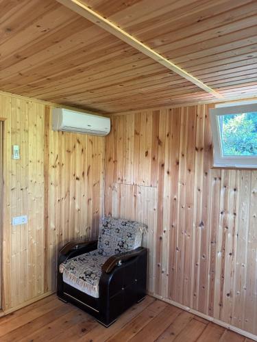 a room with a chair in a room with wooden walls at In the Forest in K'vemo Jocho