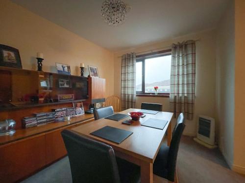 a dining room with a table with chairs and a window at Bervie Road Cottage in Kinlochbervie
