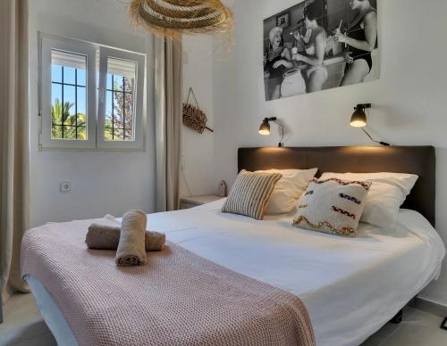 a bedroom with a large white bed and two windows at Bungalow Marquérite Moraira, 5 minutes from beach in Teulada