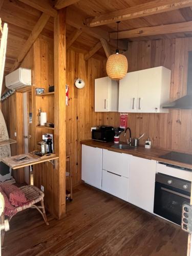 a kitchen with white cabinets and a wooden wall at Lisbon Beach Hut - Costa Caparica in Costa da Caparica