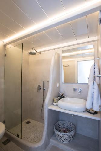 a bathroom with a glass shower and a sink at Christy Suites by Alpha Living in Mikonos