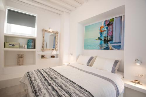 a white bedroom with a bed and a painting on the wall at Christy Suites by Alpha Living in Mikonos