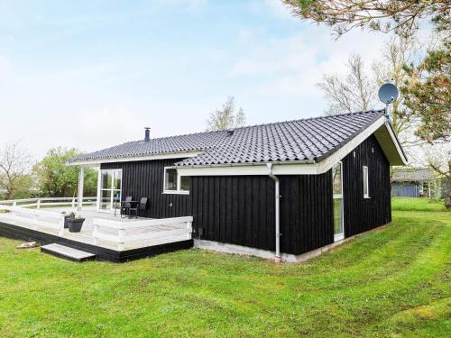 a black shed with a deck in a yard at 6 person holiday home in Fjerritslev-By Traum in Fjerritslev