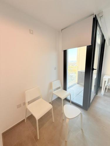a room with two white chairs and a window at E1 Simple Apartment in Gibraltar
