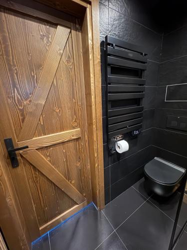 a bathroom with a wooden door and a toilet at Stodoła na Drobnym Wierchu in Podwilk