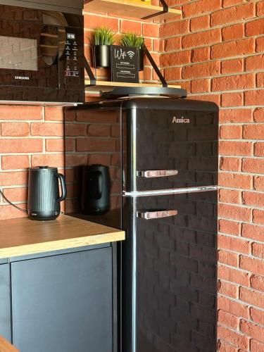 a kitchen with a refrigerator and a brick wall at Stodoła na Drobnym Wierchu in Podwilk