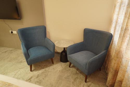 two blue chairs and a table in a room at Varay Eco Hotel in Ujjain