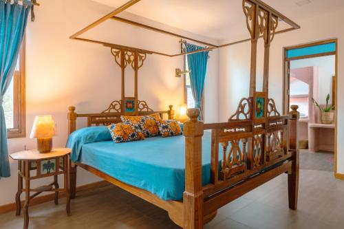 a bedroom with a wooden bed with blue sheets at Matemwe House 2 in Matemwe