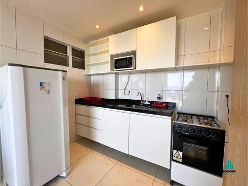 a kitchen with white cabinets and a sink and a refrigerator at Aquarius Style by Holiday Stays in Fortaleza