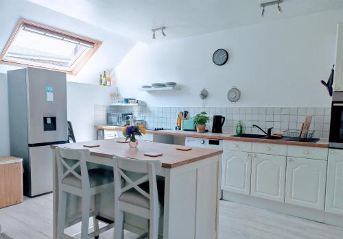 a kitchen with white cabinets and a kitchen island with stools at Cosy 1st floor loft apartment in Normandy in Céaucé