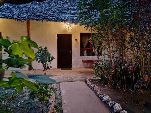 a small house with a thatch roof and a door at Paje By Night Bungalows in Paje