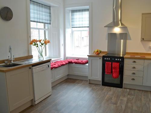 a kitchen with a stove and a sink and a window at Halleaths Home Farm in Lochmaben