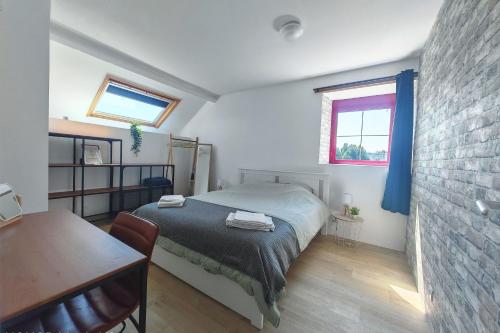 a bedroom with a bed and a table and a window at Cosy 1st floor loft apartment in Normandy in Céaucé