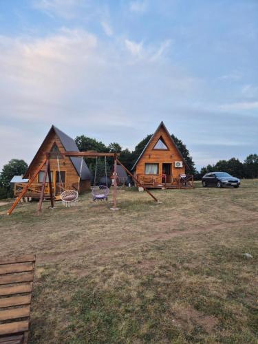 a group of three tents with a car parked in a field at The View Smrcevo Brdo in Žabljak