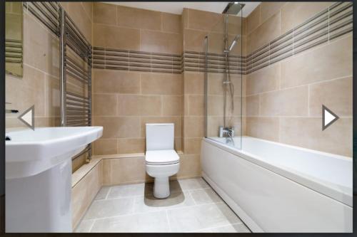 a bathroom with a toilet and a tub and a sink at Fabulous two bedroom flat with concierge in Dagenham