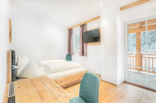 a room with a bed and a table and a window at Tyrol Mountain Aparts - Urlaubsresort Hafele in Sankt Jakob in Defereggen