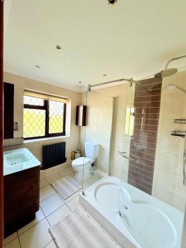a bathroom with a tub and a toilet and a sink at 6 Bedroom 4 bathroom House 14 guests or more in Birmingham, Wolverhampton, Walsall Contractors, Family & Groups in Walsall