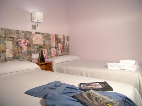 a hotel room with two beds and a book on the bed at Albergue Quinta del Jalón in Granja de San Pedro