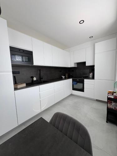 a kitchen with white cabinets and a table in it at Apartmán Pod Hvězdami in Přímětice