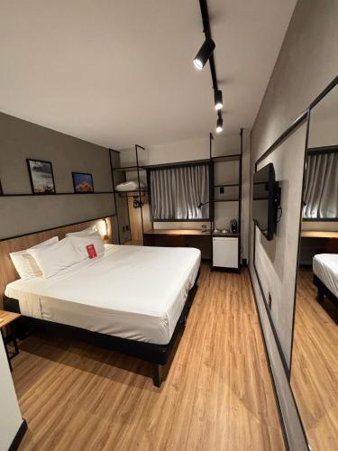 a bedroom with a large white bed and two windows at Ibis Foz do Iguaçu in Foz do Iguaçu